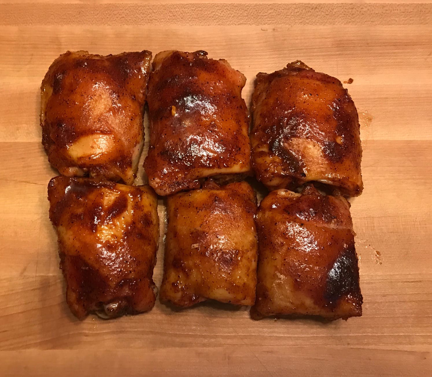 A wooden cutting board topped with six pieces of meat.