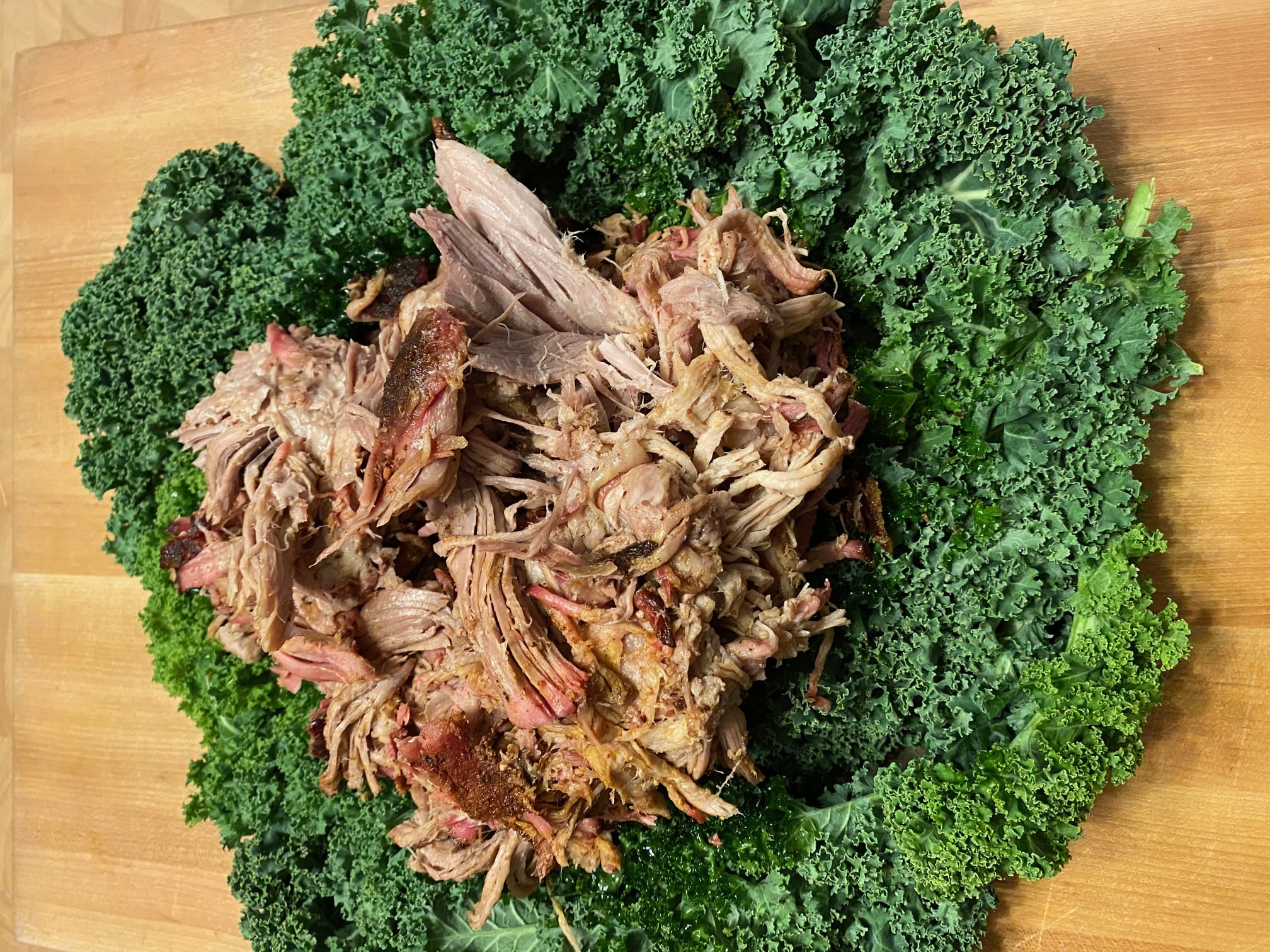 A plate of meat and greens on top of a table.